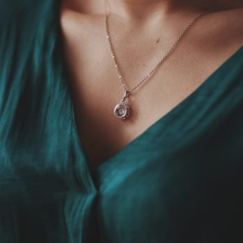 A closeup shot of a female wearing a beautiful silver necklace with a diamond pendant